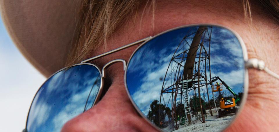 Heather Muniz watches as a crew puts the finishing touches on a new leg that was installed on the Sanibel Lighthouse on Tuesday, Jan. 23, 2024. The leg was lost in Hurricane Ian on Sept. 28, 2022. Muniz says she walks the beach every morning.