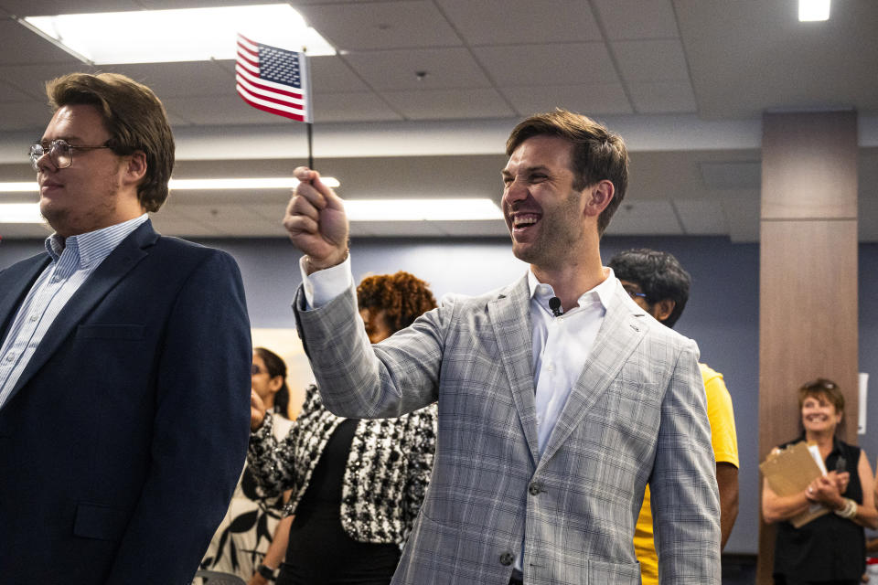 NASCAR driver Daniel Suarez waves an American flag during a naturalization ceremony, June 18, 2024, in Charlotte, N.C. (Noah Watts/Daylon Barr Photography, Trackhouse Racing via AP)