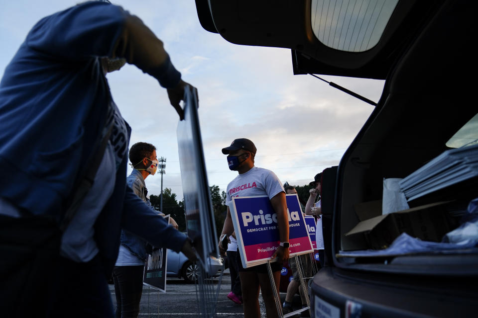 Georgia State Representative and Democratic candidate of District 44, Connie Di Cicco, back left, talks with Trinity Brockman, right, before distributing signs on Sunday, Oct. 11, 2020, in Marietta, Ga. Calling themselves sign ninjas, a group of people, including Di Cicco, routinely gather to trade and assemble campaign signs around their districts for local elections in Georgia and then venture out in the dark to install them along main thoroughfares. (AP Photo/Brynn Anderson)