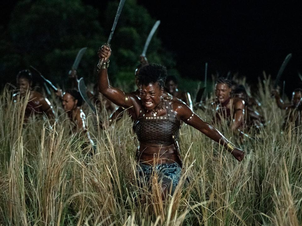 Viola Davis running through high grass with a sword in her hand