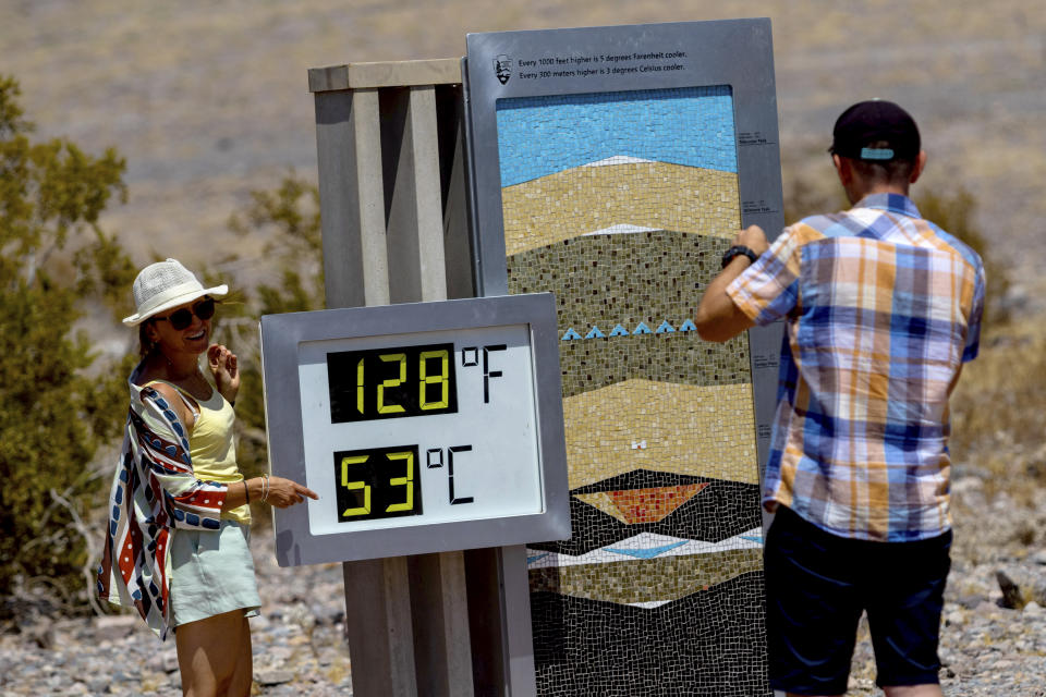 Tourists take photographs with the thermometer at the Furnace Creek Visitor Center during a dangerous heat wave, Tuesday, July 9, 2024, in Death Valley, Calif. The thermostat is imprecise, registering the temperature anywhere from 1 to 5 degrees Fahrenheit higher than more precise instruments and providing a more impressive reading for pictures. (AP Photo/Ty ONeil)