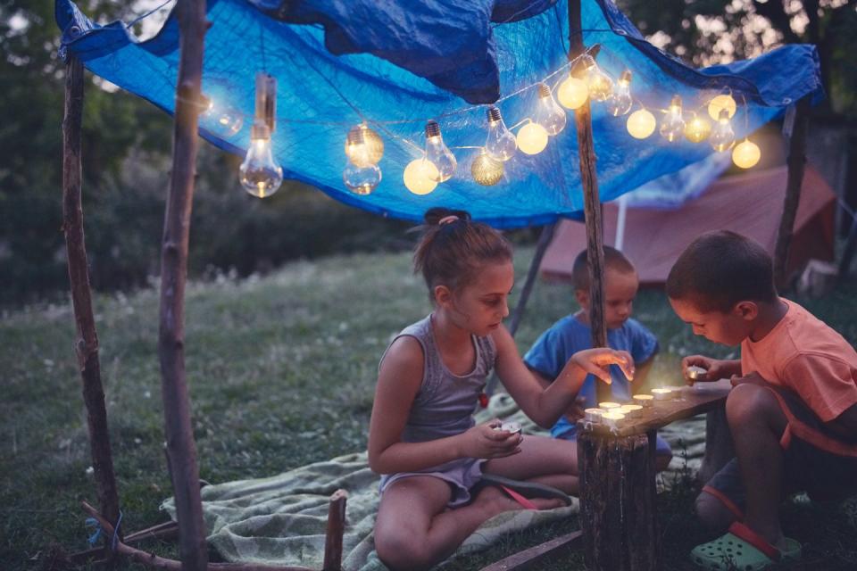 summer activities kids making a small tent with candles in the backyard