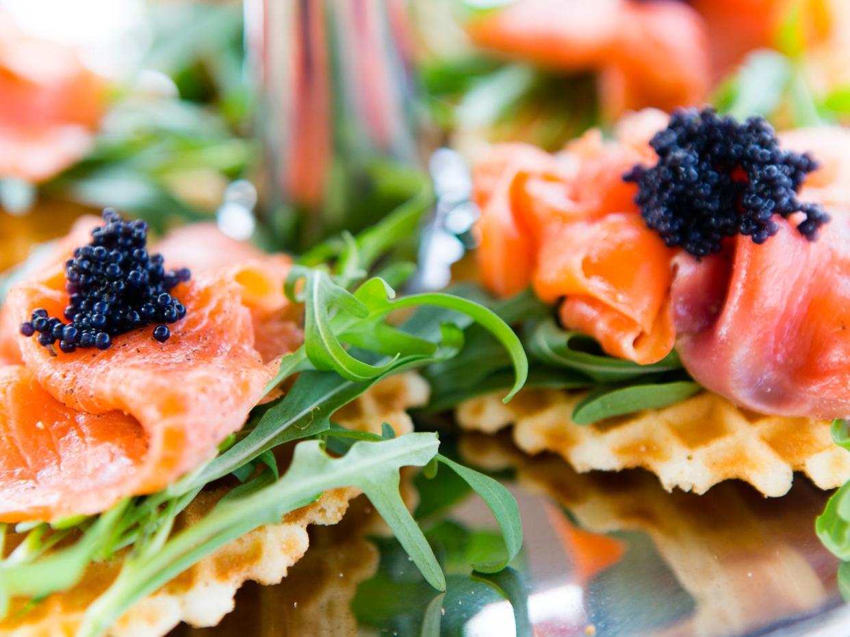 Smoked salmon, caviar, and arugula appetizer on a waffle biscuit.