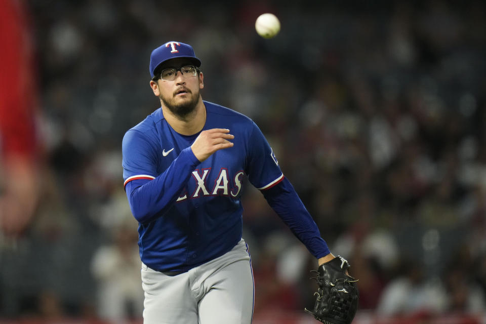 Texas Rangers starting pitcher Dane Dunning tosses the ball to first for the out on Los Angeles Angels' Jo Adell during the fourth inning of a baseball game Wednesday, Sept. 27, 2023, in Anaheim, Calif. (AP Photo/Jae C. Hong)