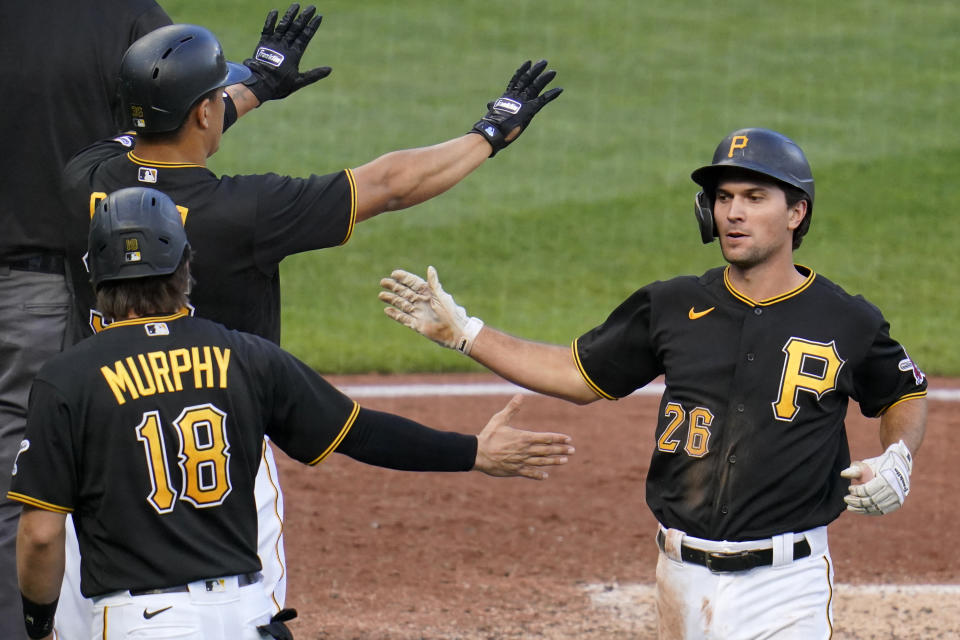 Pittsburgh Pirates' Adam Frazier (26) is welcomed by John Ryan Murphy (18) and Jose Osuna, left rear, after they scored on a single by Pittsburgh Pirates' Ke'Bryan Hayes off St. Louis Cardinals starting pitcher Carlos Martinez, and an error by right fielder Tommy Edman, during the fourth inning of the first baseball game of a doubleheader in Pittsburgh, Friday, Sept. 18, 2020. (AP Photo/Gene J. Puskar)