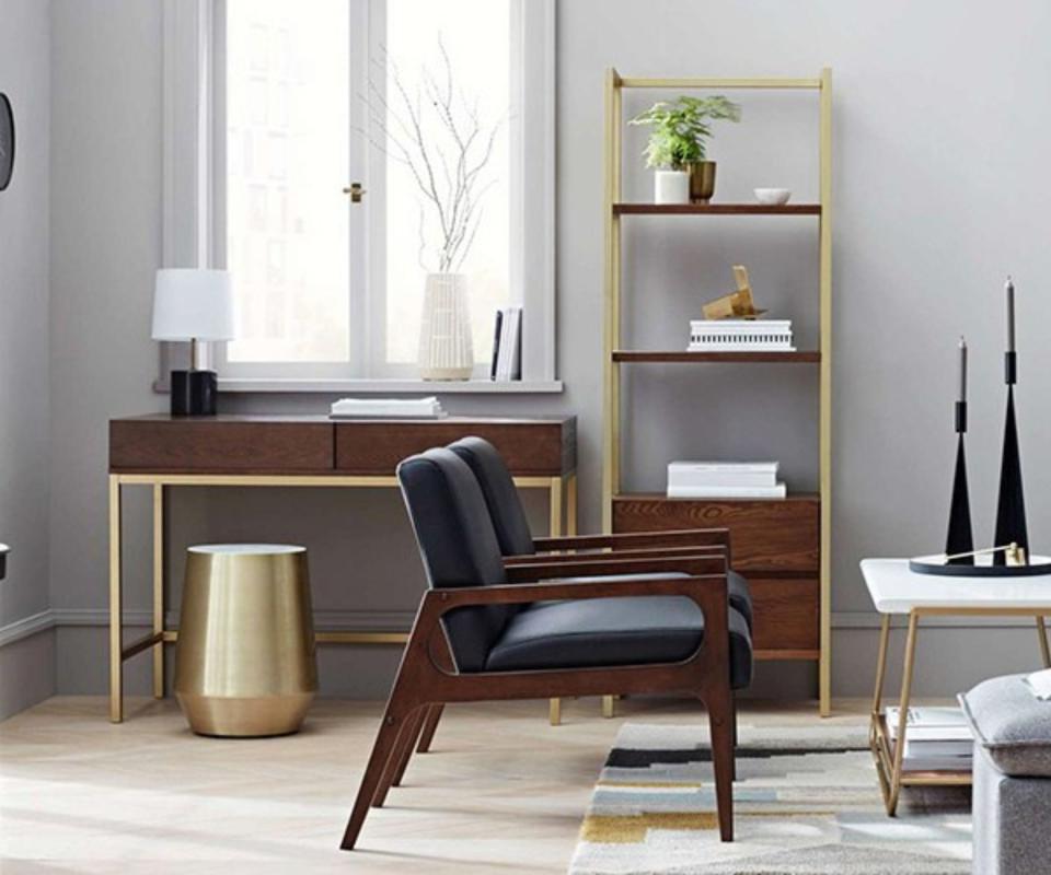 A gray living room with bench, bookshelves and a desk.