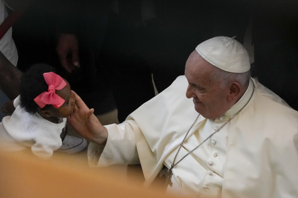 Pope Francis caresses a child as he leaves the parish of Serafina at the end of a meeting with representatives of some aid and charity centers ahead of Sunday's 37th World Youth Day in Lisbon, Friday, Aug. 4, 2023. Francis is in Portugal through the weekend to preside over the jamboree that St. John Paul II launched in the 1980s to encourage young Catholics in their faith. The Argentine Jesuit has picked up John Paul's mantle with gusto as he seeks to inspire the next generation to rally behind his crucial social justice and environmental priorities.(AP Photo/Gregorio Borgia)