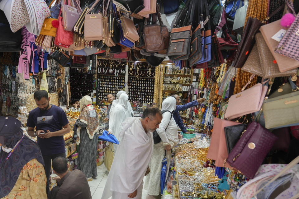 Pilgrims buy souvenirs and bags at a shop outside the Grand Mosque during the annual Hajj pilgrimage in Mecca, Saudi Arabia, Saturday, June 24, 2023. Straw hats, cross-body bags, and collapsible chairs are some essentials pilgrims have on them as they perform the Hajj. The fifth pillar of Islam is a profoundly spiritual experience but requires practical and specific preparation to deal with hours of walking in scorching temperatures, camping stints, and massive crowds. (AP Photo/Amr Nabil)