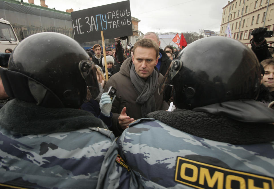 FILE - Opposition leader Alexey Navalny, speaks with riot police officers blocking the way during a protest rally against Prime Minister Vladimir Putin's rule in St. Petersburg, Russia, Feb. 25, 2012. The poster reads: 'We will not be frighten". (AP Photo, File)