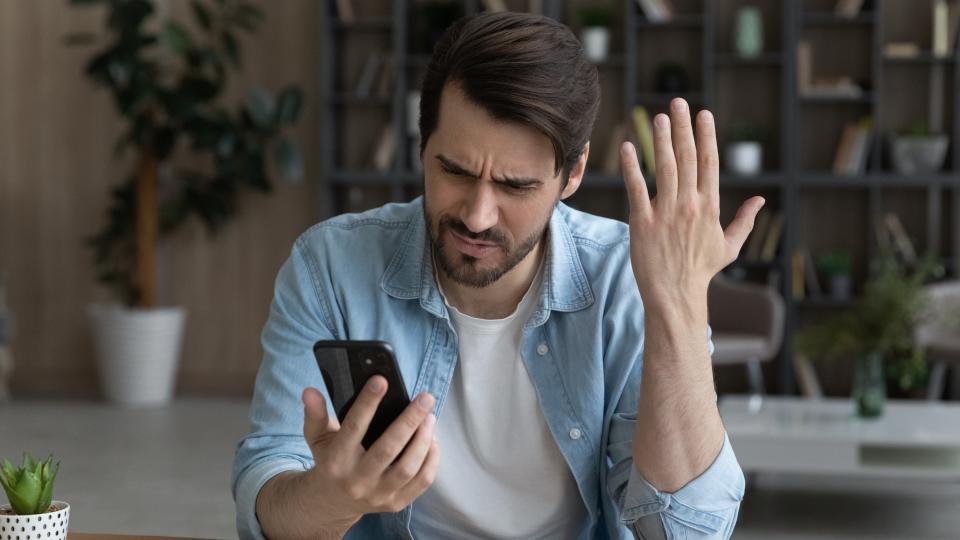 A frustrated man looking at his smartphone