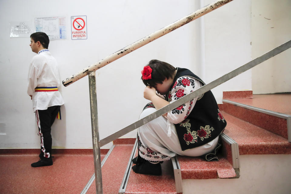 In this Dec. 3, 2019, photograph a girl with Down syndrome wipes her eyes before performing in a dance show, in Bucharest, Romania. Children with Down syndrome staged a fashion show and performed along a ballet ensemble, two milestone events for the inclusion of people with disabilities in Romania's social life, 30 years after the fall of communism following a violent uprising at the end of 1989.(AP Photo/Vadim Ghirda)