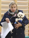 A woman holding a dog prepares to cast her ballot in an election to the Polish parliament in Warsaw, Poland, on Oct. 13, 2019. Poles are voting Sunday in a parliamentary election, that the ruling party of Jaroslaw Kaczynski is favored to win easily, buoyed by the popularity of its social conservatism and generous social spending policies that have reduced poverty. (AP Photo/Czarek Sokolowski)