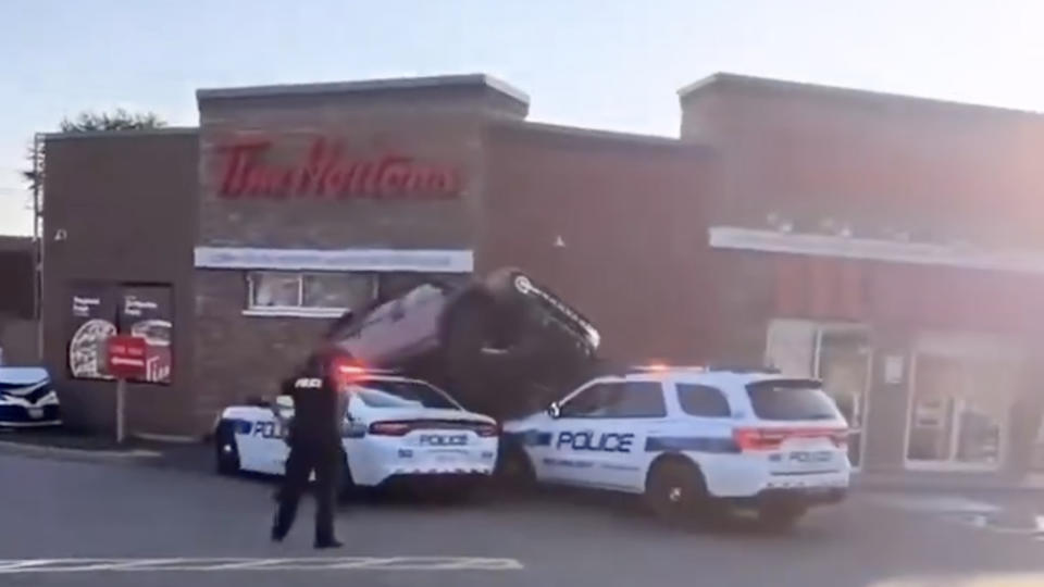 Ford Bronco tries to drive over Dodge Durango police vehicle in Tim Horton's drive-thru line.