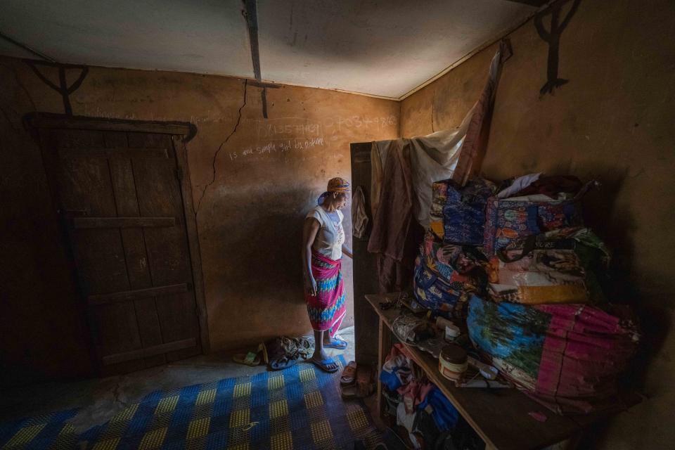 Roseline Ujah, 49, exits her home in Umuida, Nigeria, Friday, Feb. 11, 2022. Ujah's husband Godwin fell severely ill with a fever and cough. Everyone assumed at first that the palm wine tapper had contracted malaria, but then he failed to improve on medications for that disease. Doctors at a local hospital diagnosed him with COVID-19, though there were no tests available locally to confirm their suspicion. (AP Photo/Jerome Delay)