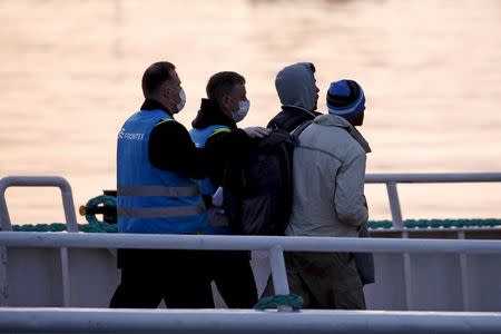 Frontex officers escort migrants boarding on a Turkish-flagged passenger boat to be returned to Turkey, on the Greek island of Lesbos, April 4, 2016. REUTERS/Giorgos Moutafis