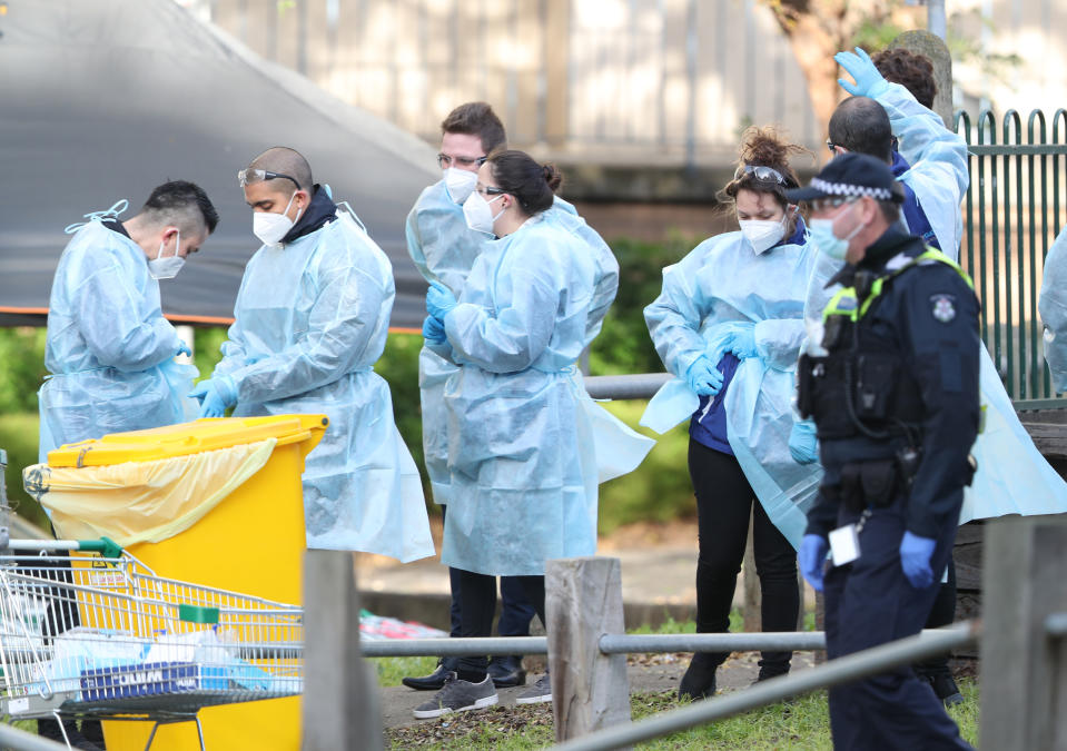 Medical workers and police are seen at a Government Commission tower in North Melbourne which remains under strict lockdown in Melbourne, Saturday, July 18, 2020. Victoria recorded 428 coronavirus cases on Friday, the highest daily increase since the start of the pandemic. (AAP Image/David Crosling) NO ARCHIVING