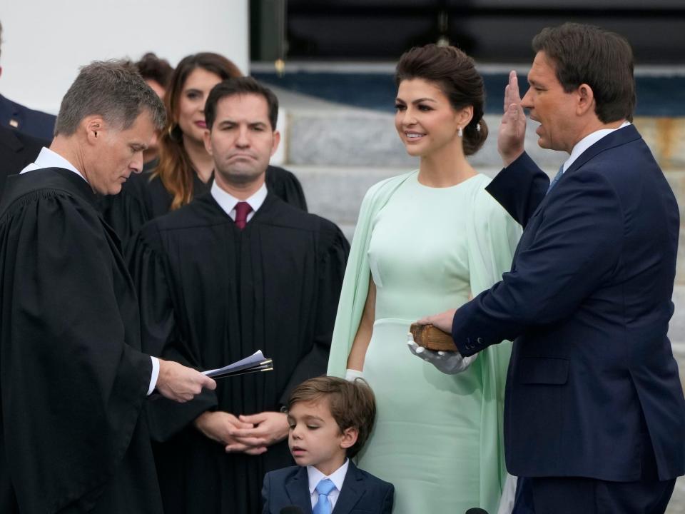 Florida Gov. Ron DeSantis, right, is sworn by Florida Supreme Court Chief Justice Carlos Muniz, left, to begin his second term during an inauguration ceremony outside the Old Capitol Tuesday, January 3, 2023, in Tallahassee, Florida. Looking on is DeSantis' wife Casey, second from right, and their son Mason.
