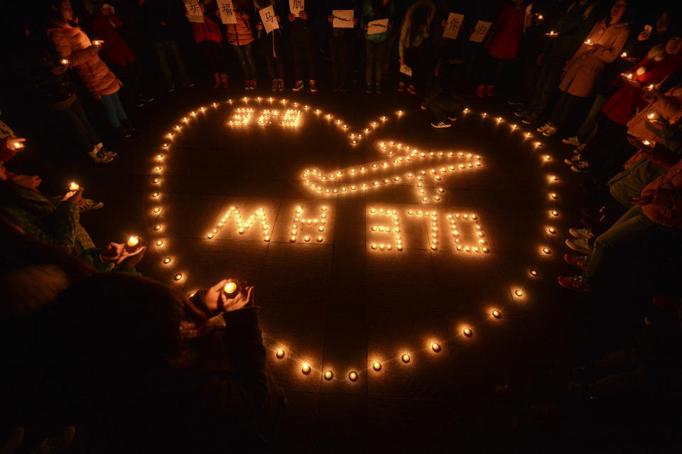 In this Thursday, March 13, 2014 photo, university students hold a candlelight vigil for passengers on the missing Malaysia Airlines Flight 370 in Yangzhou, in eastern China's Jiangsu province. With the search for the missing airliner entering its eighth day, scenarios involving piracy or hijacking are increasingly being talked about as possible explanations for the disappearance of the Boeing 777 with 239 people on board. (AP Photo) CHINA OUT