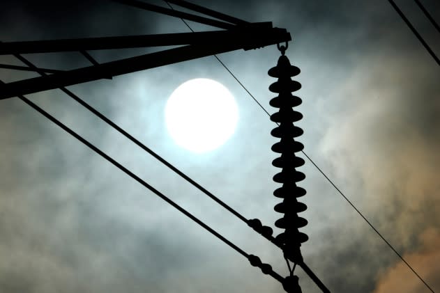 The sun rises over power lines Tuesday, June 27, 2023, in Houston. Meteorologists say scorching temperatures brought on by a heat dome have taxed the Texas power grid and threaten to bring record highs to the state. (AP Photo/David J. Phillip)