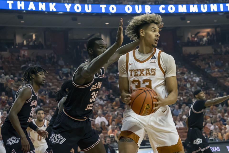 Texas forward Tre Mitchell, right, looks to pass against Oklahoma State forward Moussa Cisse, left, during the first half of an NCAA college basketball game, Saturday, Jan. 22, 2022, in Austin, Texas. (AP Photo/Michael Thomas)