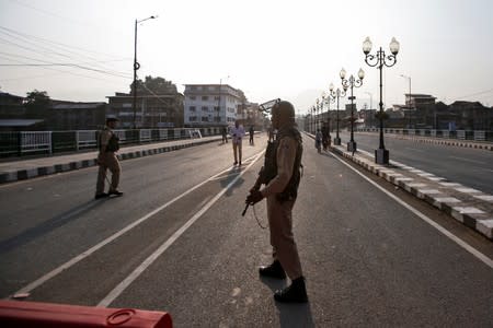 Indian security personnel stand guard on a deserted road during restrictions in Srinagar