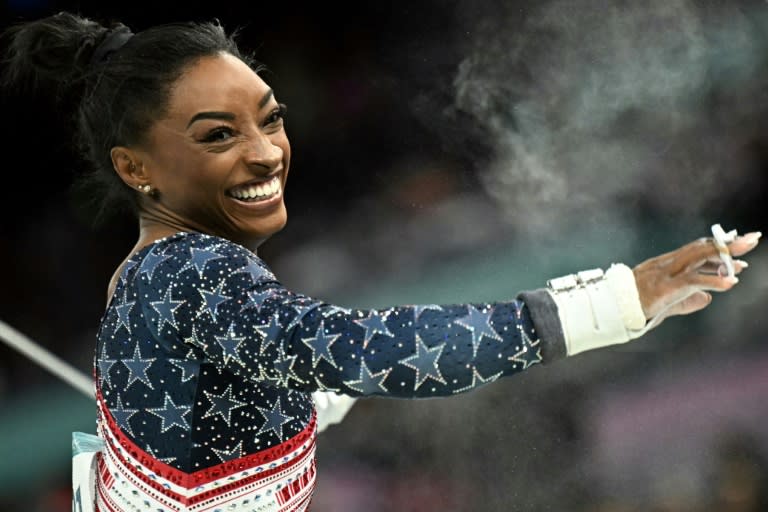 La gimnasta estadounidense Simone Biles sonríe tras su ejercicio en las barras asimétricas en el concurso olímpico por equipos, en el Bercy Arena de París el 30 de julio de 2024 (Lionel BONAVENTURE)