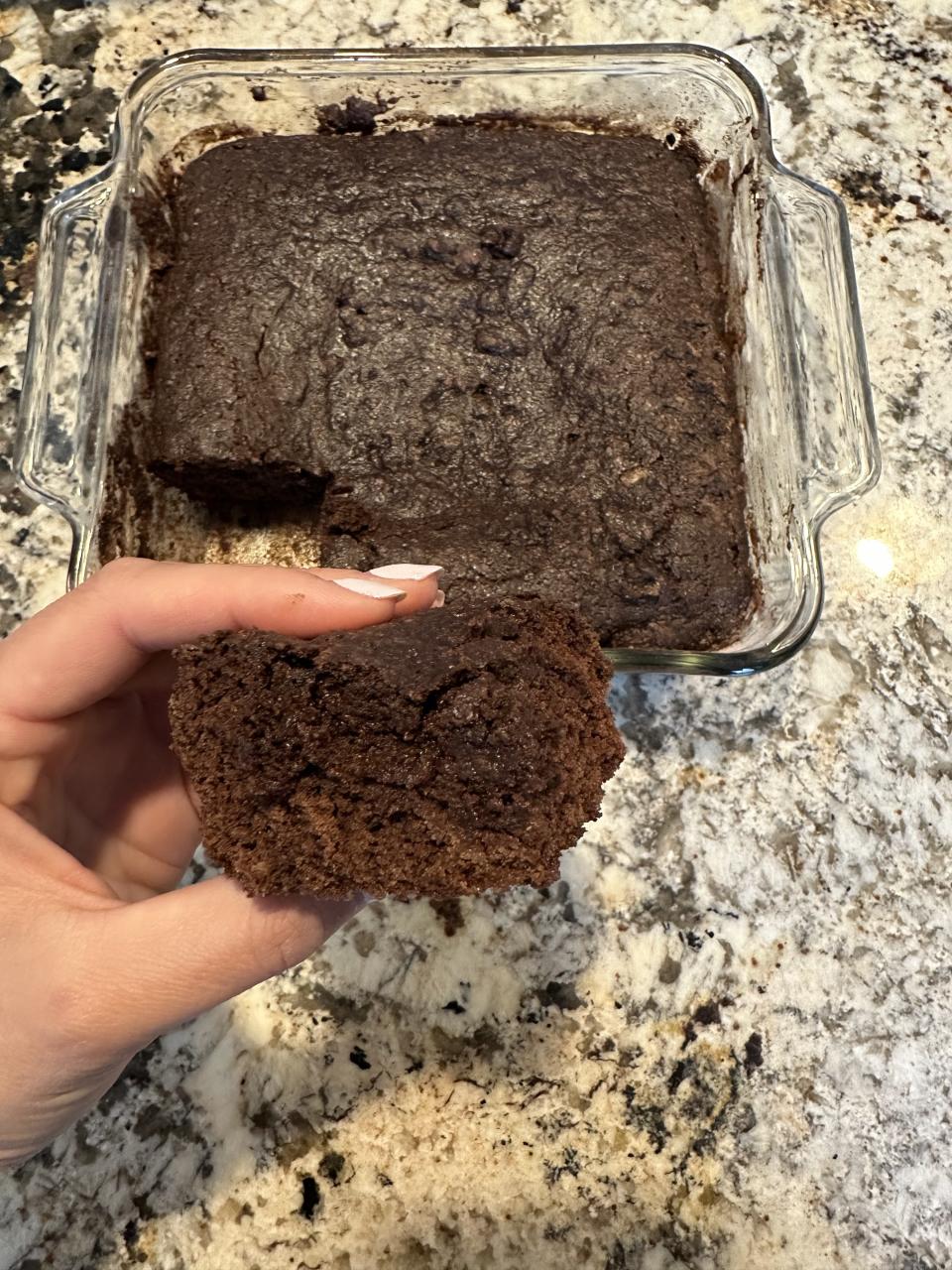 the author holding up a square of the cake