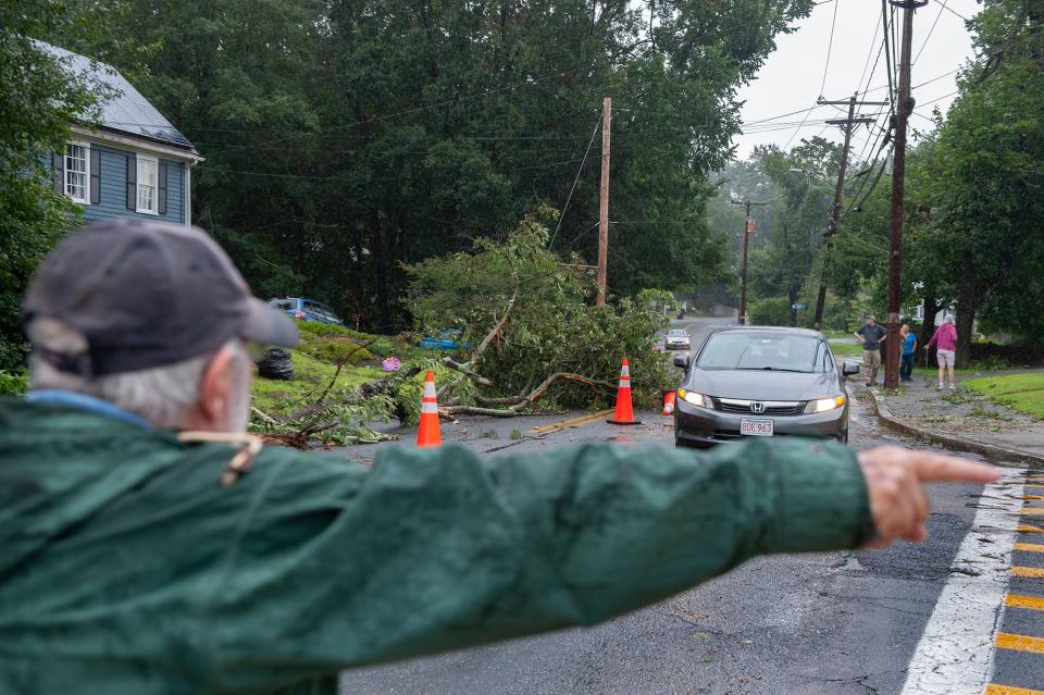 Framingham resident Patrick Mulcahy directs traffic on Brook Street, which was closed to traffic after a quick-moving storm that toppled trees throughout the neighborhood Tuesday, July 25, 2023.