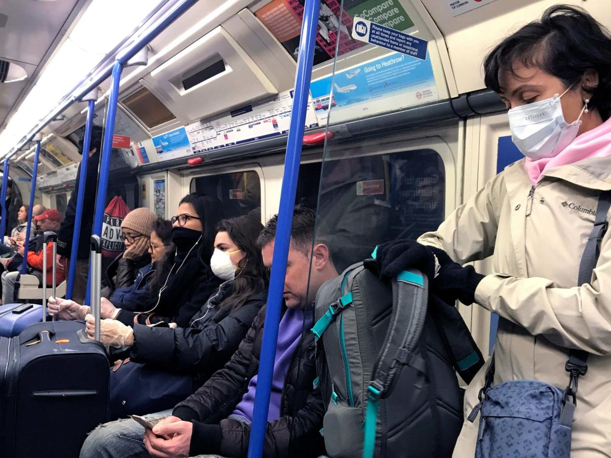 People wear masks and gloves as they travel on a tube in London, Friday, March 13, 2020: AP