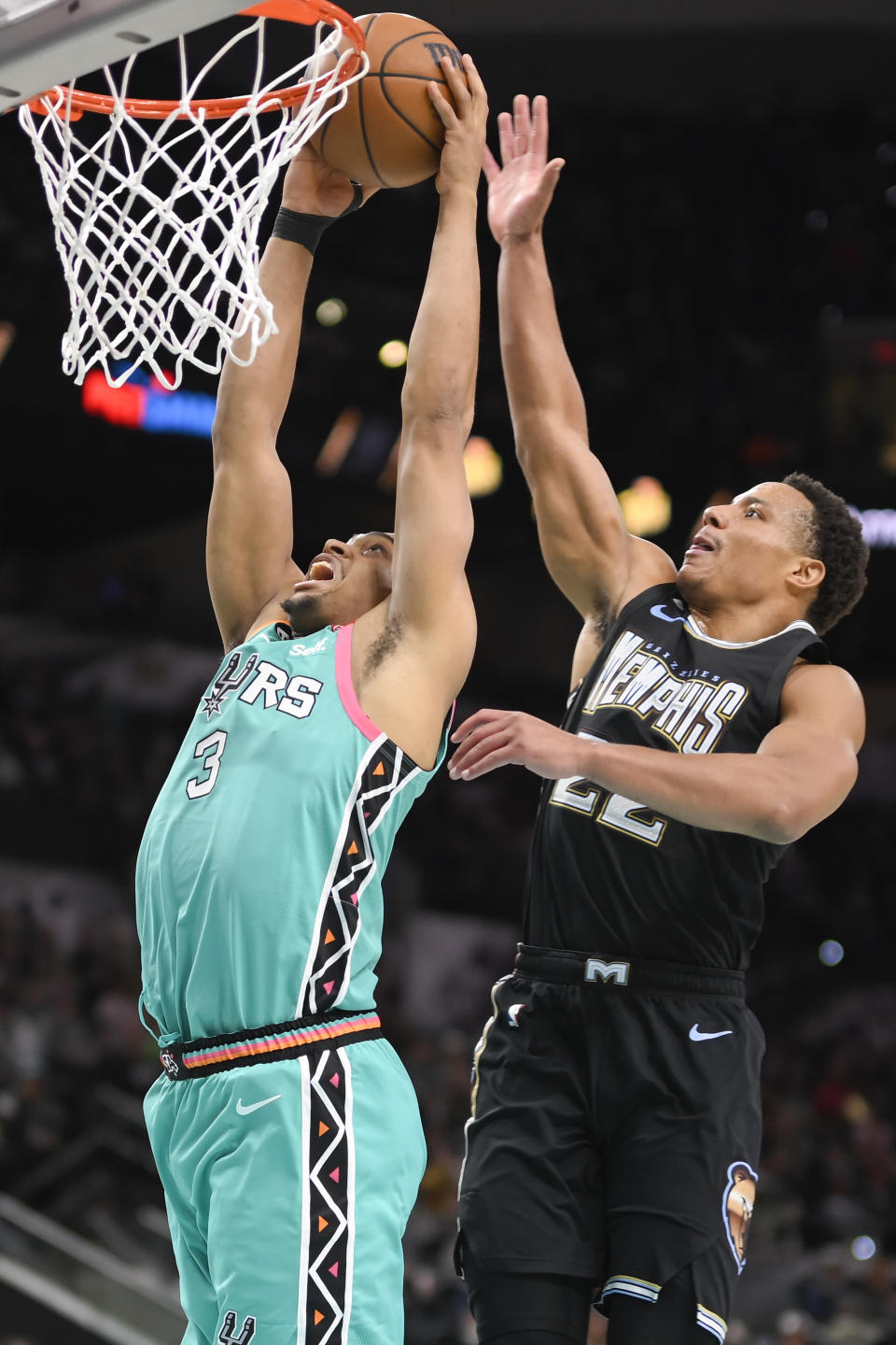 San Antonio Spurs' Keldon Johnson (3) dunks against Memphis Grizzlies' Desmond Bane during the first half of an NBA basketball game, Friday, March 17, 2023, in San Antonio. (AP Photo/Darren Abate)