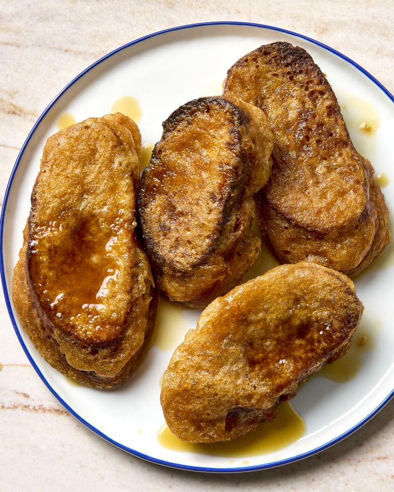 overhead shot of torrejas on a white plate with blue trim, drizzled with syrup.