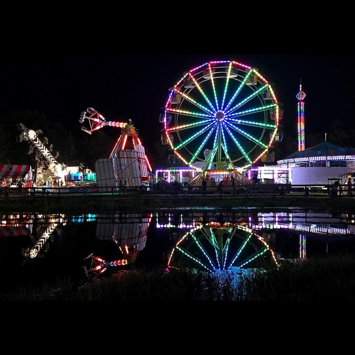 Rides are reflected in a pond during the 2017 Bolton Fair.