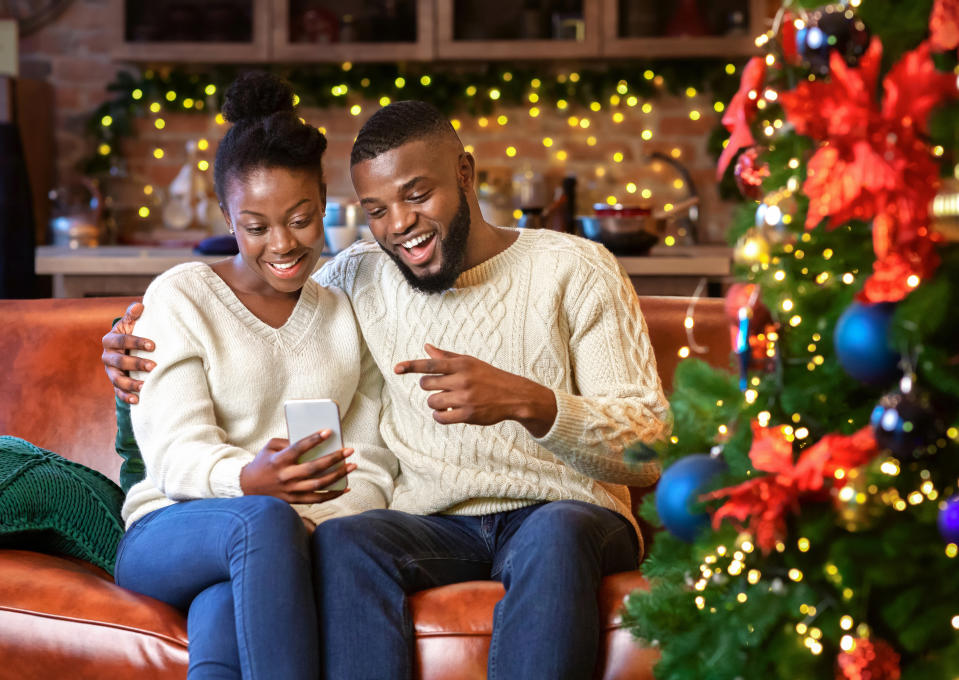 Happy african american couple making video call with smartphone, greeting their family with Christmas or New Year holidays.