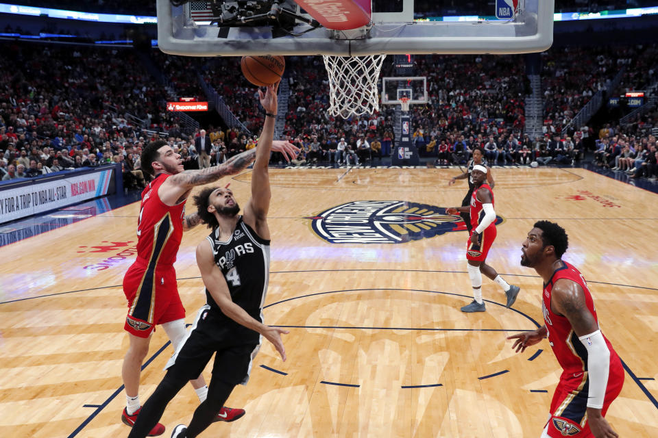 San Antonio Spurs guard Derrick White (4) goes up against New Orleans Pelicans guard Lonzo Ball, left, and forward Derrick Favors in the first half of an NBA basketball game in New Orleans, Wednesday, Jan. 22, 2020. (AP Photo/Gerald Herbert)