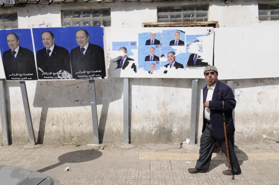 A man walks past electoral posters for incumbent President Abdelazis Bouteflika, left, and candidate Ali Benflis, Tuesday, April 15, 2014 in Algiers. Boycotting is the main form of protest against a vote President Abdelaziz Bouteflika is expected to win despite his glaring absence. Six candidates are running for the powerful presidency in the April 17 elections. (AP Photo/Ouahab Hebbat)