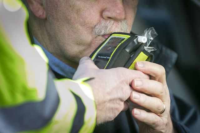 A driver blows into a PSNI Road Policing officers' breathalyser during a random drink driving checkpoint in Belfast.