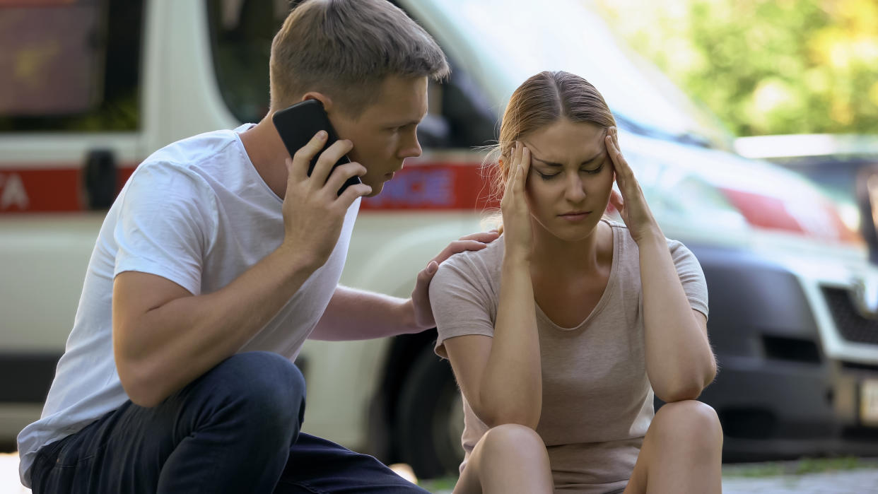 Female suffering headache, not indifferent man calling ambulance, first aid