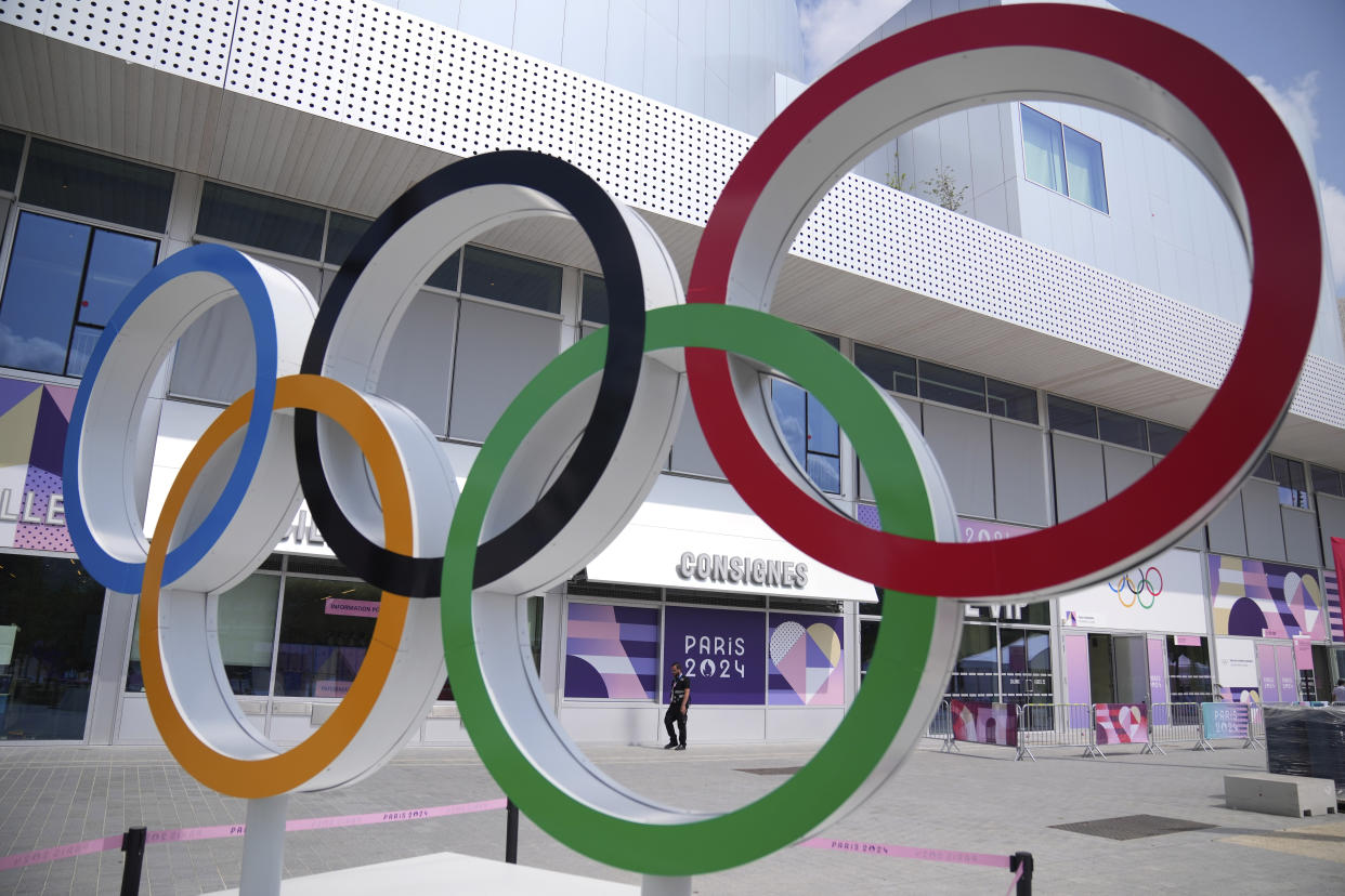 Large outdoor display of the Olympic rings near a building.