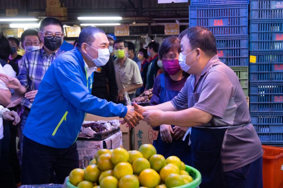 視察三重果菜市場向攤商致意。