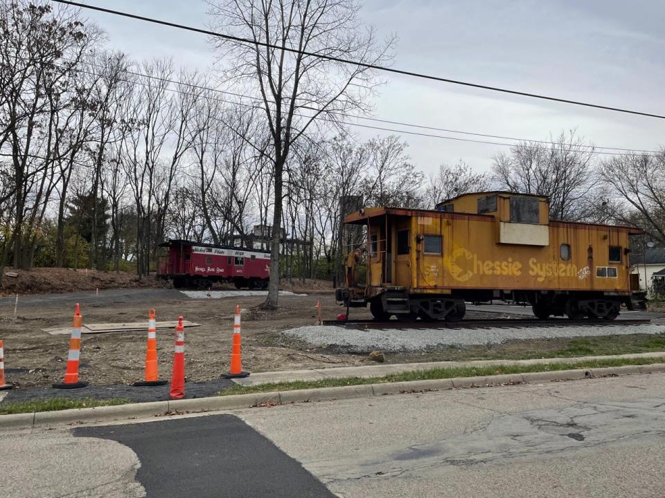 The yellow and red caboose sit in a parking lot.
