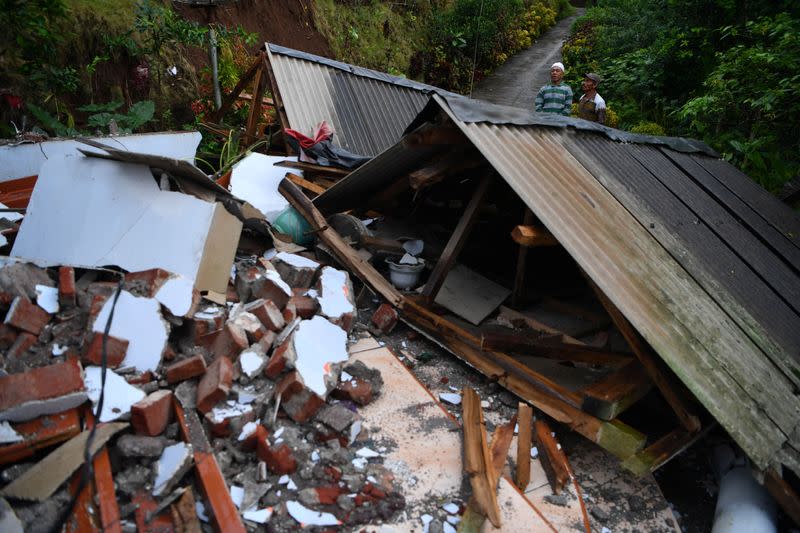 Men stand near a damaged house affected by an earthquake in Lumajang