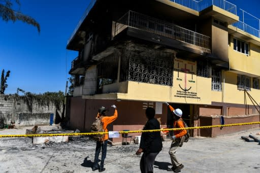 Firefighters speak to a local judge (C) as they point at the Orphanage of the Church of Bible Understanding where a fire broke out the previous night in the Kenscoff area outside of Port-au-Prince February 14, 2020