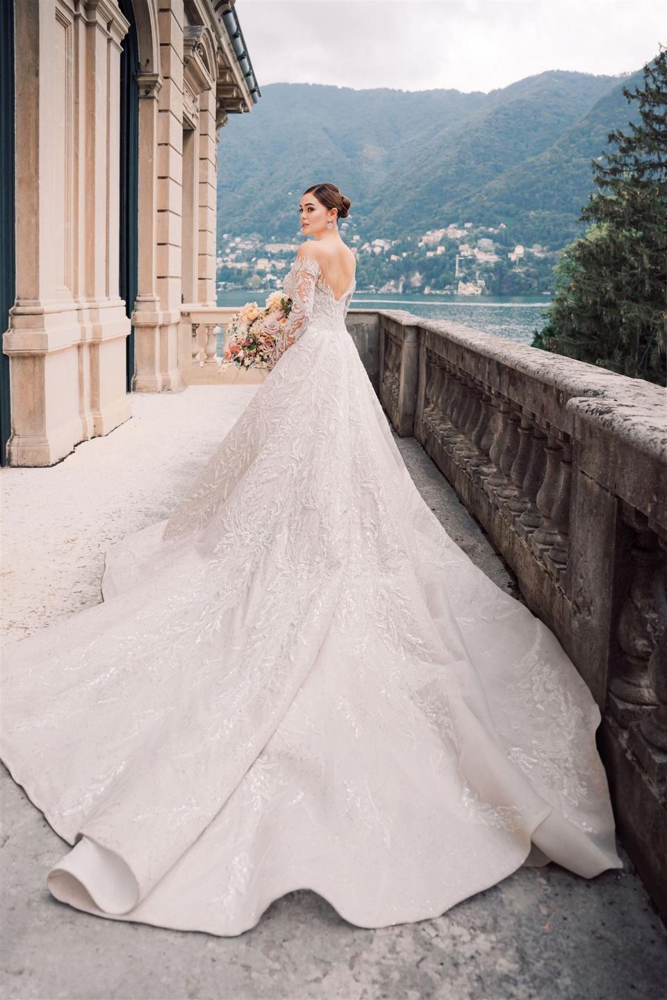 A bride stands on a balcony in her patterned wedding dress.