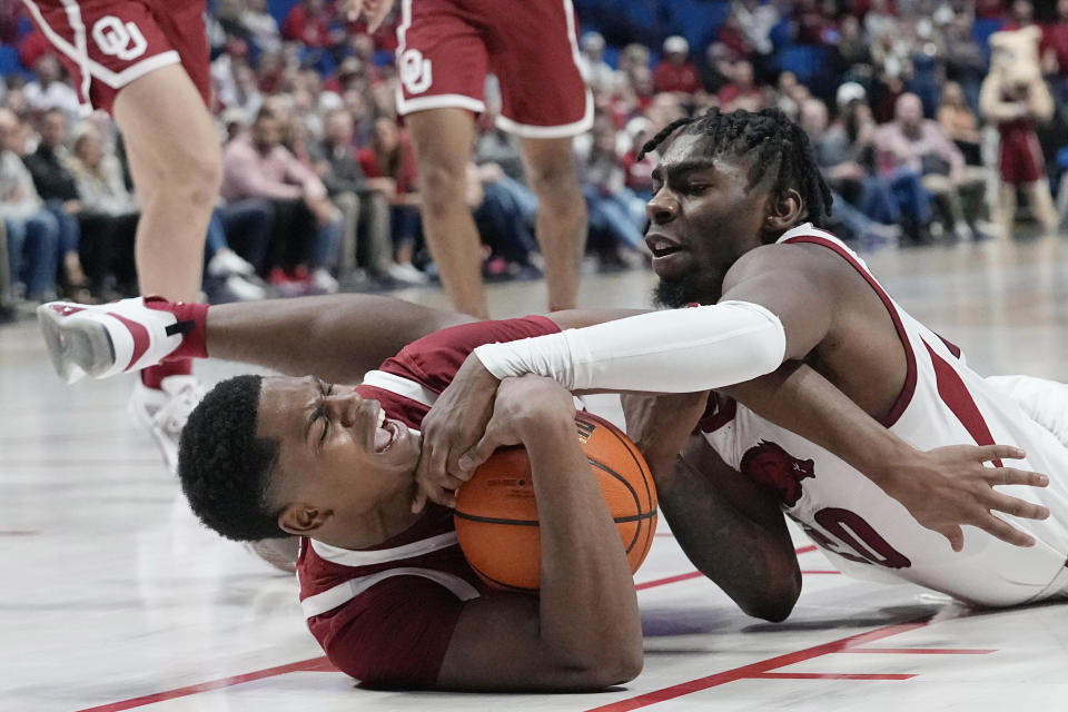 Oklahoma guard Grant Sherfield, left, and Arkansas forward Kamani Johnson, right, fight for control of the ball in the second half of an NCAA college basketball game Saturday, Dec. 10, 2022, in Tulsa, Okla. (AP Photo/Sue Ogrocki)