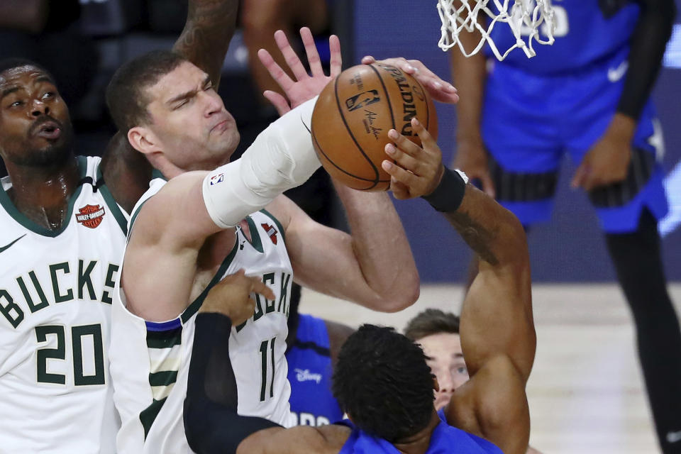 Milwaukee Bucks center Brook Lopez (11) blocks the shot of Orlando Magic forward Khem Birch, foreground, during the second half of Game 1 of an NBA basketball first-round playoff series, Tuesday, Aug. 18, 2020, in Lake Buena Vista, Fla. (Kim Klement/Pool Photo via AP)