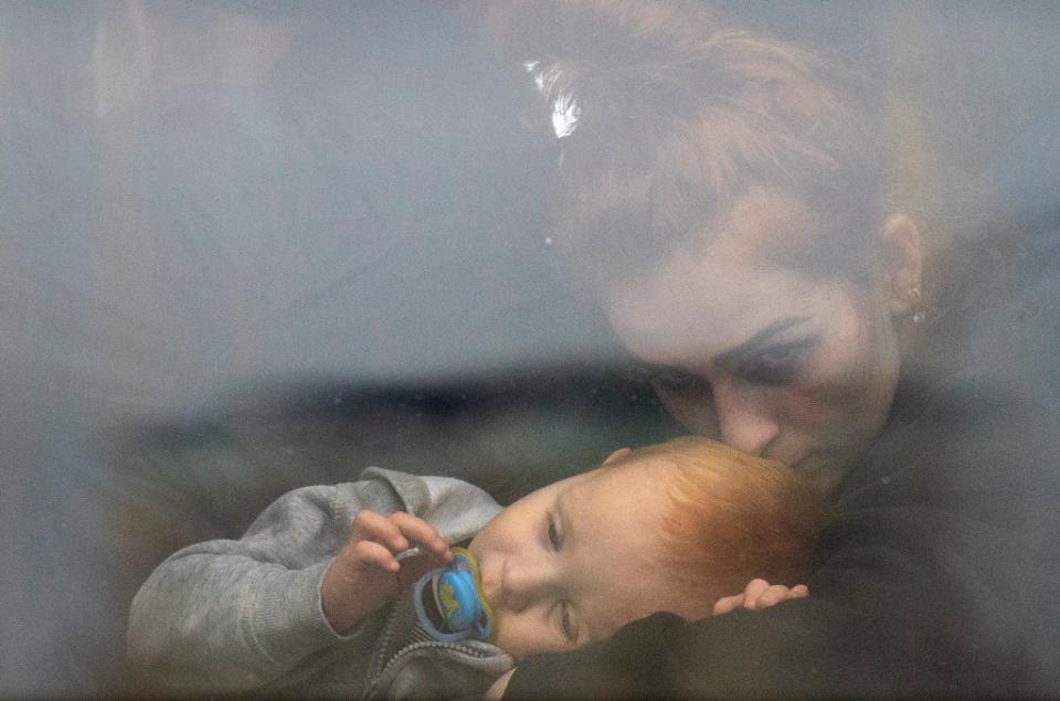 A woman holds her baby inside a bus as they leave Kyiv, Ukraine (AP)