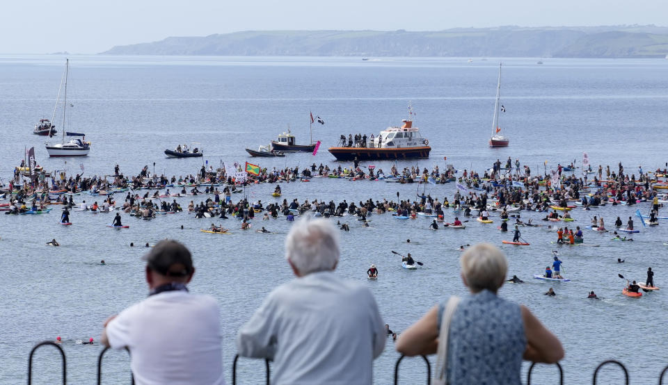 Paddleboarders and surfers take part in a paddle out to raise awareness for climate action in the sea at Gyllyngvase Beach in Falmouth, Cornwall, England, Saturday, June 12, 2021. Leaders of the G7 gather for a second day of meetings on Saturday, in which they will discuss COVID-19, climate, foreign policy and the economy. (AP Photo/Alastair Grant)