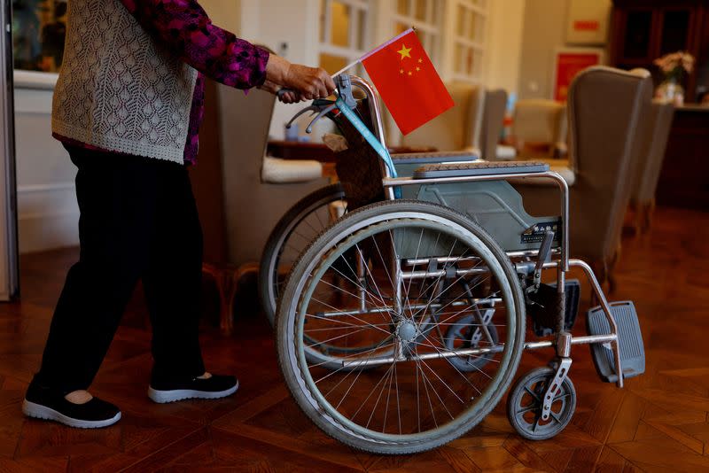 FILE PHOTO: Resident pushes a wheelchair while holding a Chinese national flag at a care home for the elderly, in Beijing