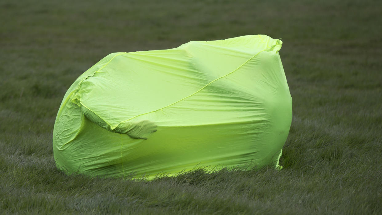  A green bothy bag in a field with people inside it. 