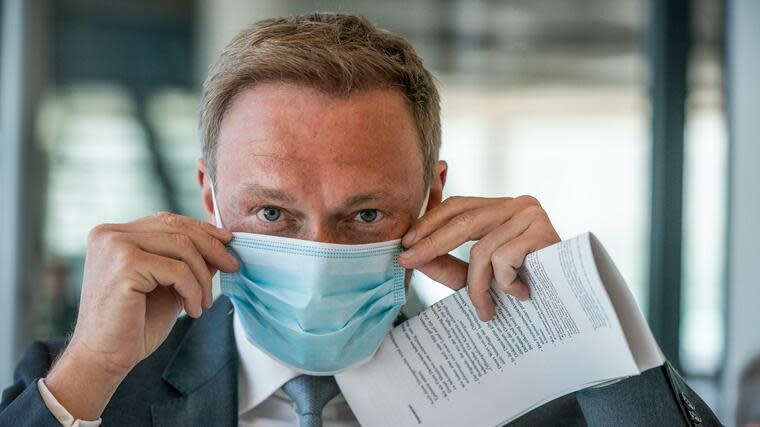 Christian Lindner rückt einen Mundschutz zurecht Foto: dpa